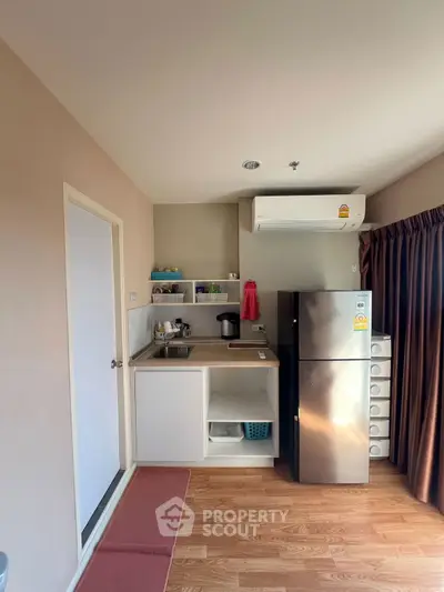 Compact kitchen with modern appliances and wooden flooring in cozy apartment