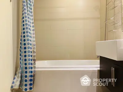 Modern bathroom with a clean white bathtub, stylish vanity cabinet, and a playful blue polka dot shower curtain enhancing the space's appeal.