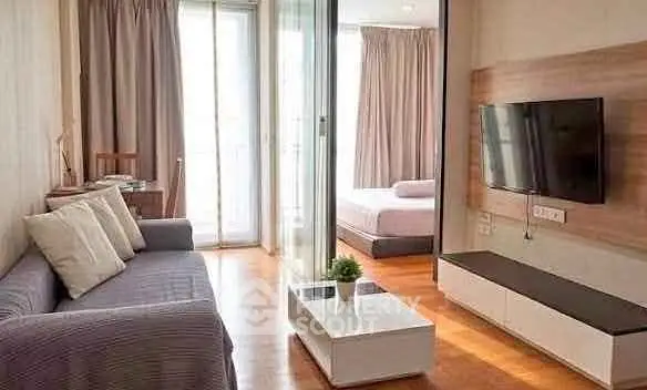 Modern living room with sleek furniture and a view into a cozy bedroom, perfect for urban living.