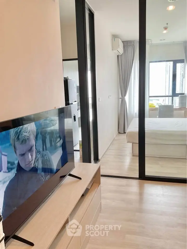 Modern apartment interior with sleek design, featuring a cozy living area and a bright bedroom separated by glass doors.