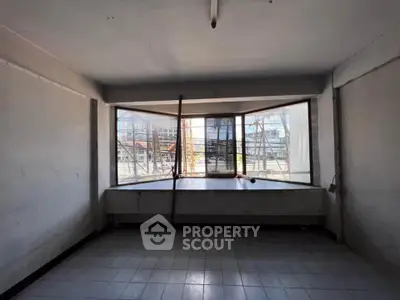 Spacious room with large windows offering construction site view, ideal for renovation.