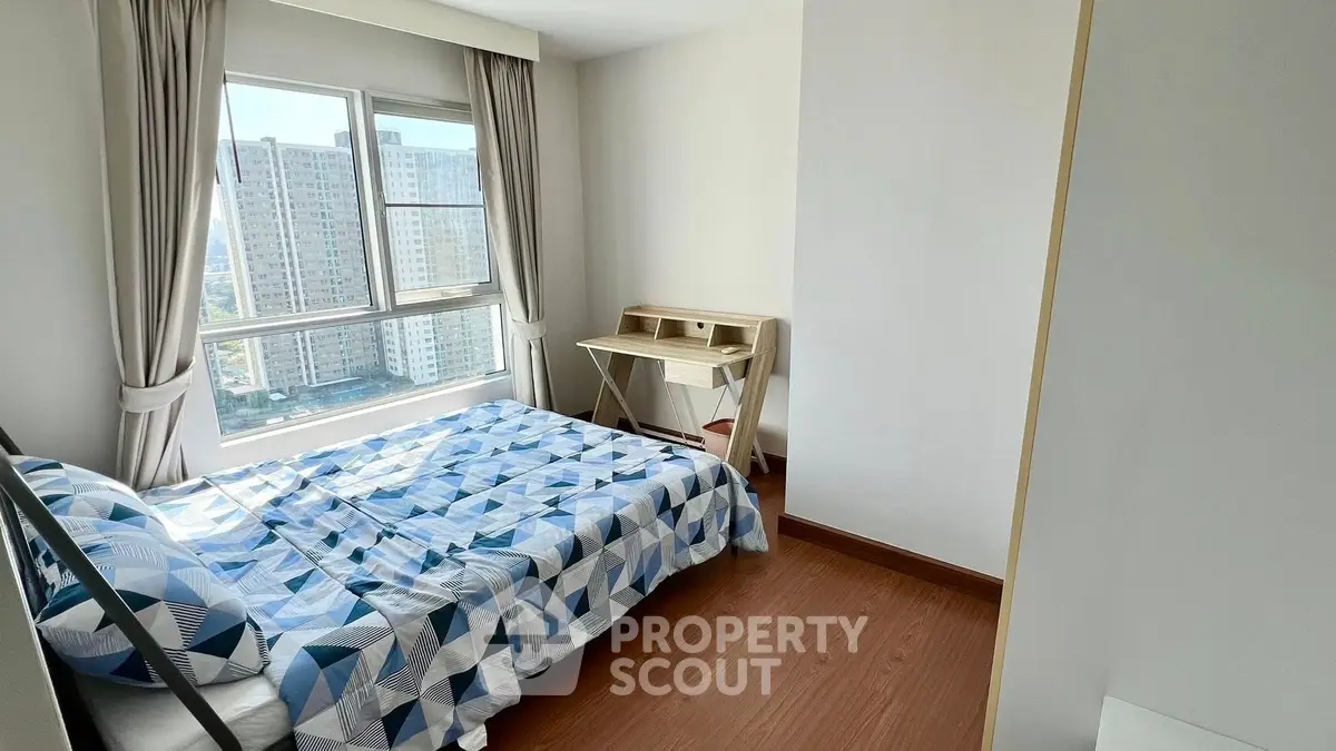 Bright bedroom with large window and modern decor in high-rise apartment.