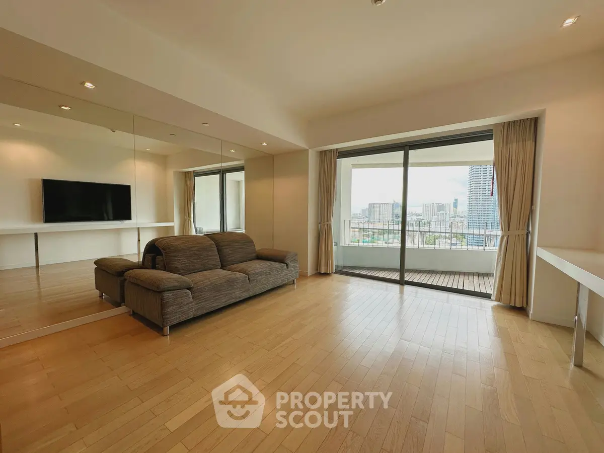 Spacious living room with large balcony and city view, featuring modern sofa and mirrored wall.