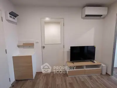 Modern living room with sleek TV setup and air conditioning in a stylish apartment.
