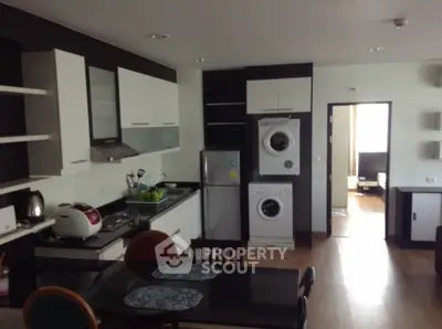 Modern kitchen with appliances including washing machine and fridge in open layout design.