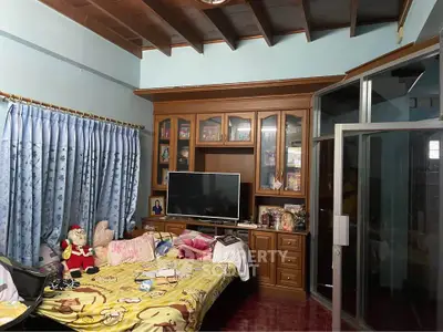 Cozy living room with wooden ceiling and glass doors, featuring a TV and decorative cabinet.