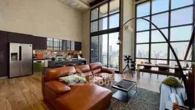 Luxurious loft with floor-to-ceiling windows and stunning city views, featuring modern kitchen and spacious living area.