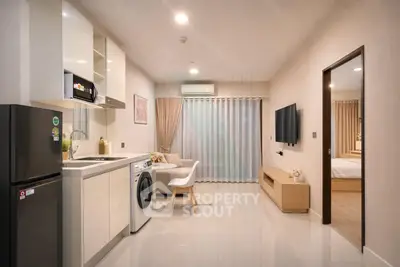 Modern open-plan living room with kitchen, featuring sleek appliances and cozy seating area.