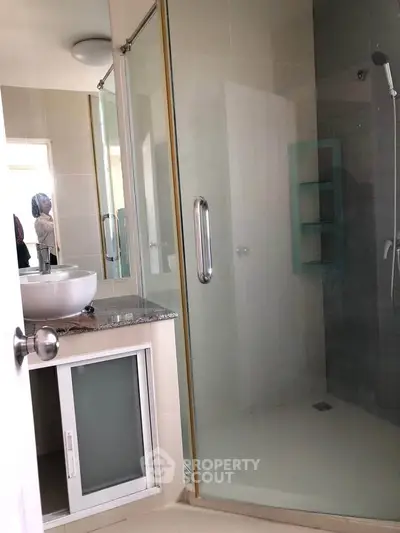 Modern bathroom with glass shower and sleek vanity in a contemporary home.