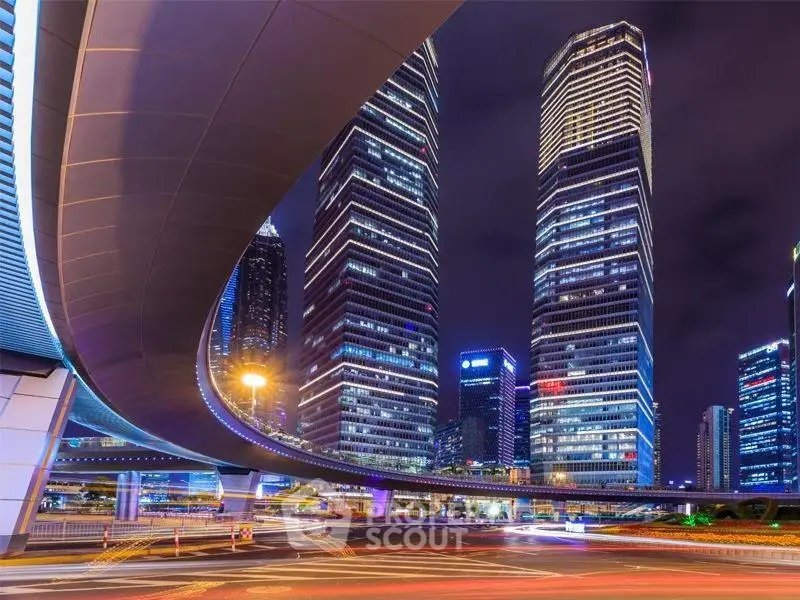 Stunning night view of modern skyscrapers with illuminated cityscape and dynamic overpass.