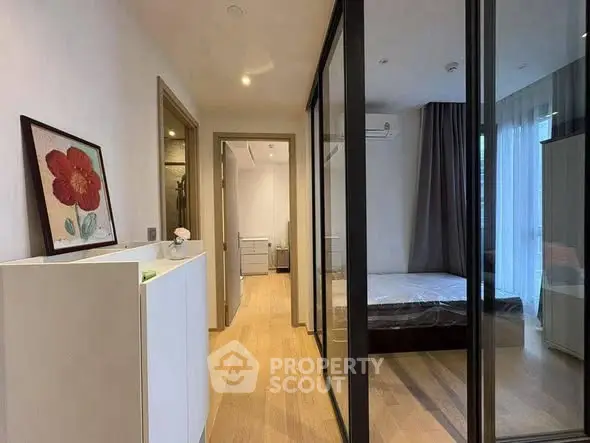 Modern bedroom with glass partition and wooden flooring, featuring stylish decor and natural light.