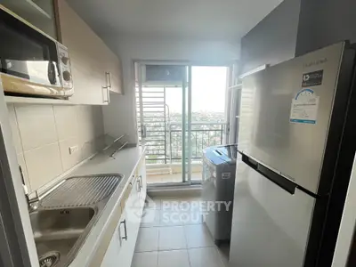 Compact kitchen with modern appliances and balcony view in urban apartment