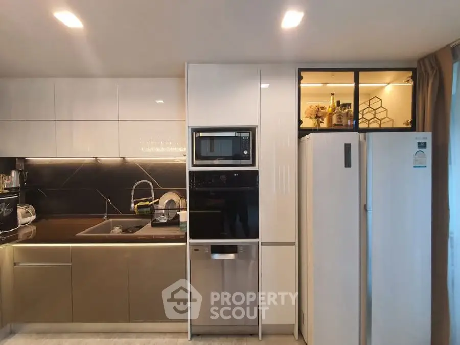 Modern kitchen with sleek appliances and stylish cabinetry, featuring a built-in microwave and spacious fridge.