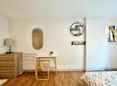 Chic bedroom with modern decor and wooden flooring, featuring a stylish mirror and cozy furnishings.