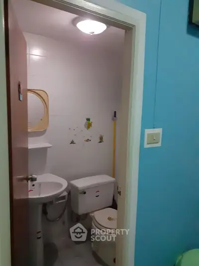 Compact bathroom with white fixtures and colorful wall decals, ideal for small spaces.