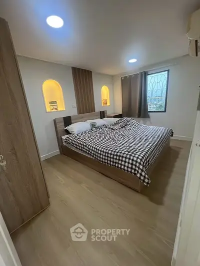 Cozy bedroom with modern decor and natural light, featuring a stylish bed and wooden flooring.