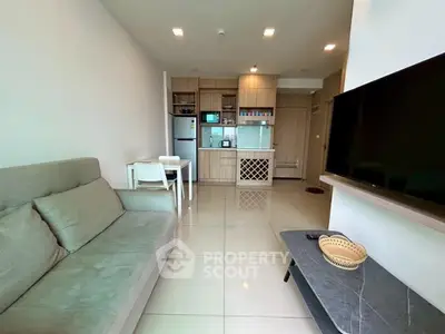 Modern living room with sleek kitchen, cozy sofa, and wall-mounted TV in open layout apartment.
