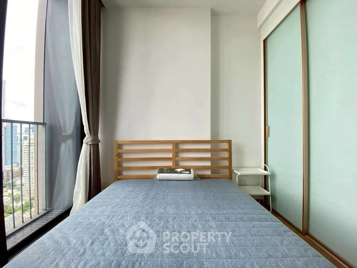 Modern bedroom with large window and city view, featuring minimalist design and sliding closet doors.