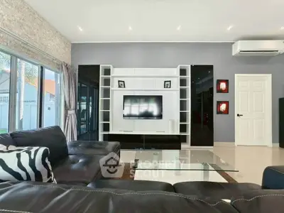 Modern living room with sleek black leather sofas and stylish entertainment center.