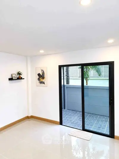 Bright modern room with sliding glass doors leading to a private patio, featuring minimalist decor and recessed lighting.
