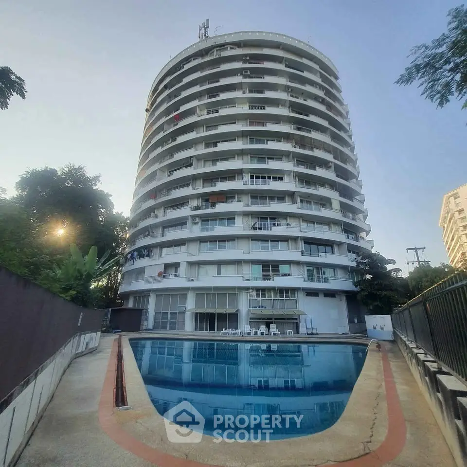 Stunning high-rise building with pool in serene setting, perfect for luxury living.