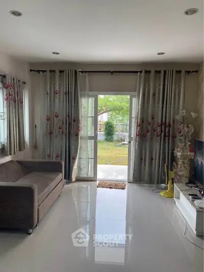 Spacious living room with elegant curtains and garden view, perfect for relaxation and family gatherings.