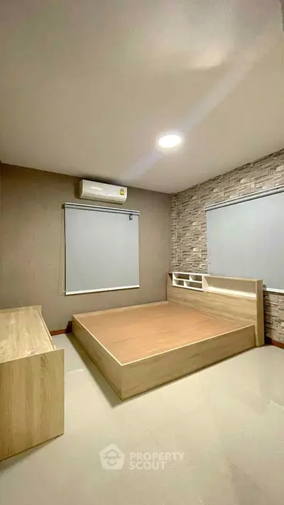 Modern bedroom with minimalist design and stone accent wall, featuring built-in air conditioning and sleek furniture.