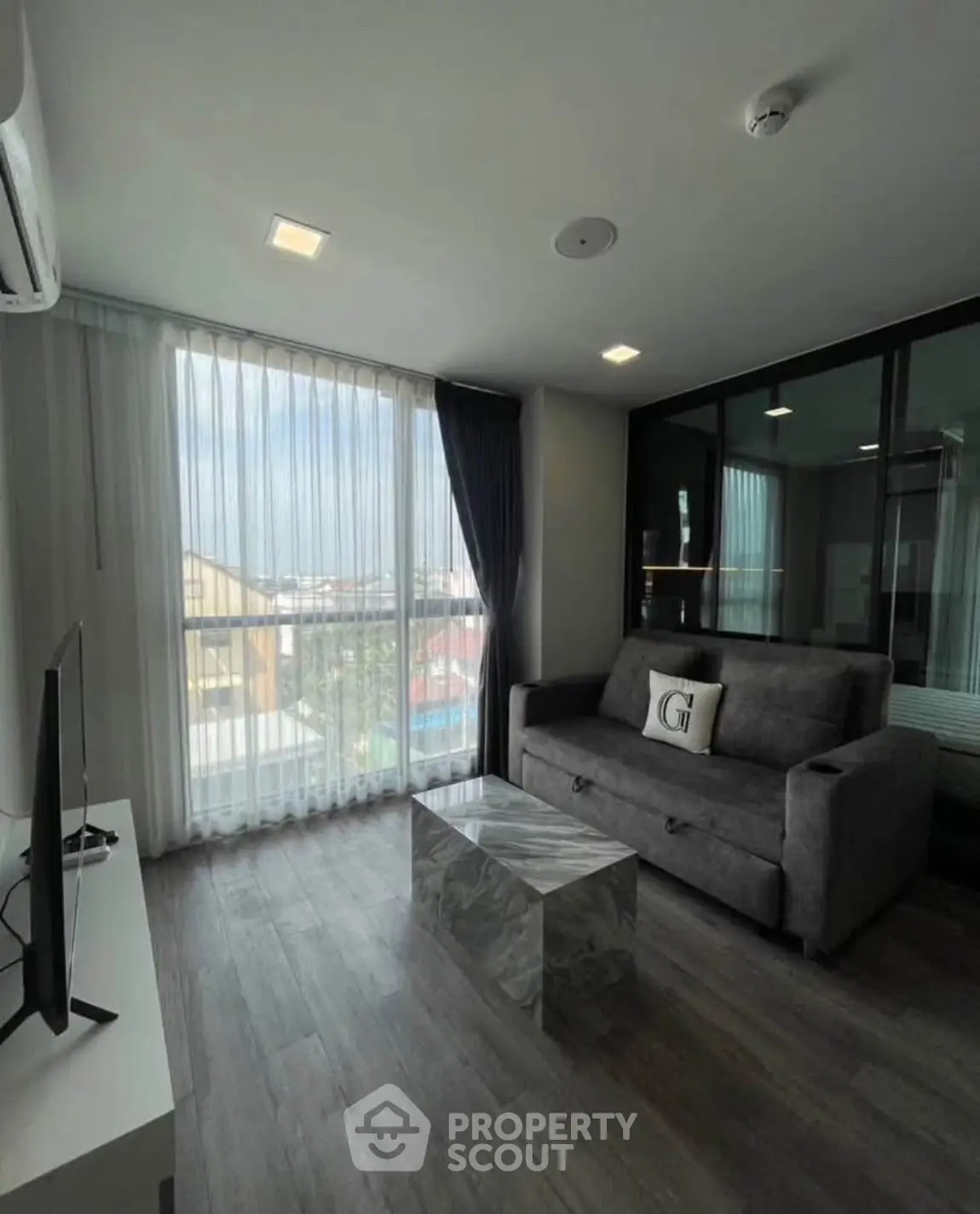 Modern living room with large window and stylish furniture in a high-rise apartment.