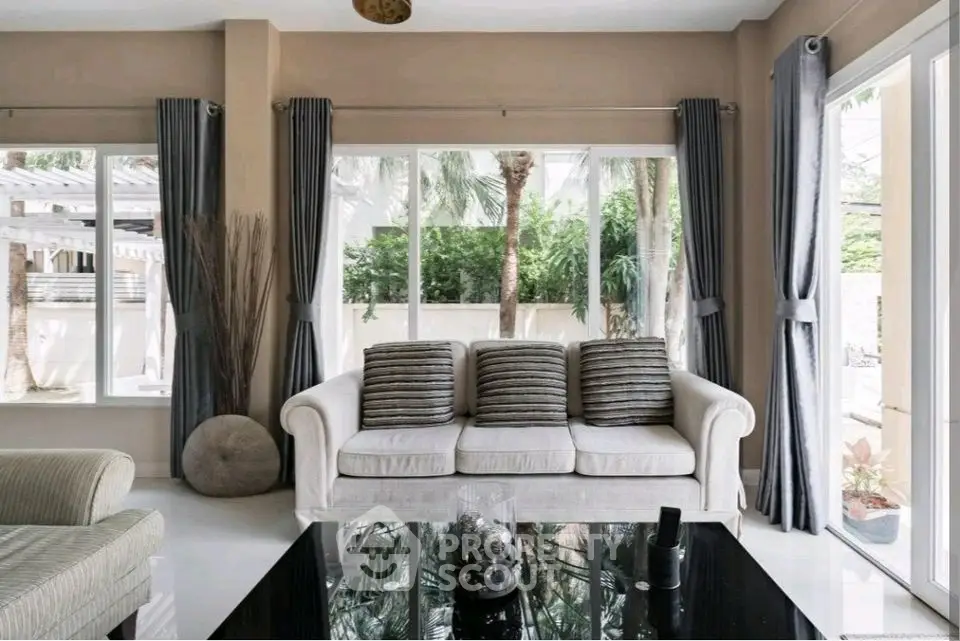Elegant living room with large windows and modern decor, perfect for relaxation.