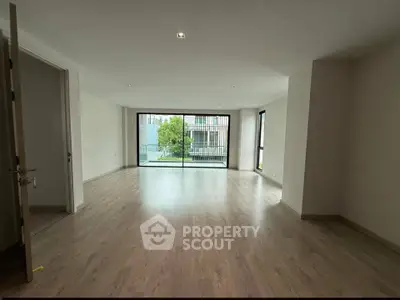Spacious modern living room with large windows and wooden flooring, offering a bright and airy atmosphere.