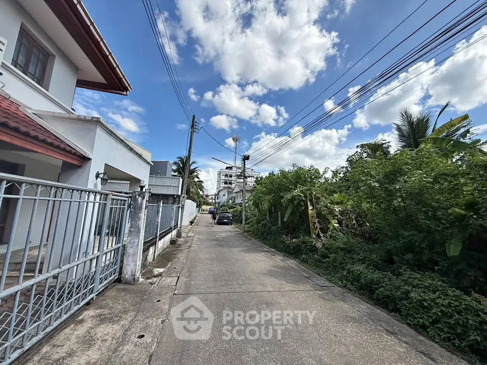 Charming residential street view with lush greenery and clear blue sky, perfect for serene living.