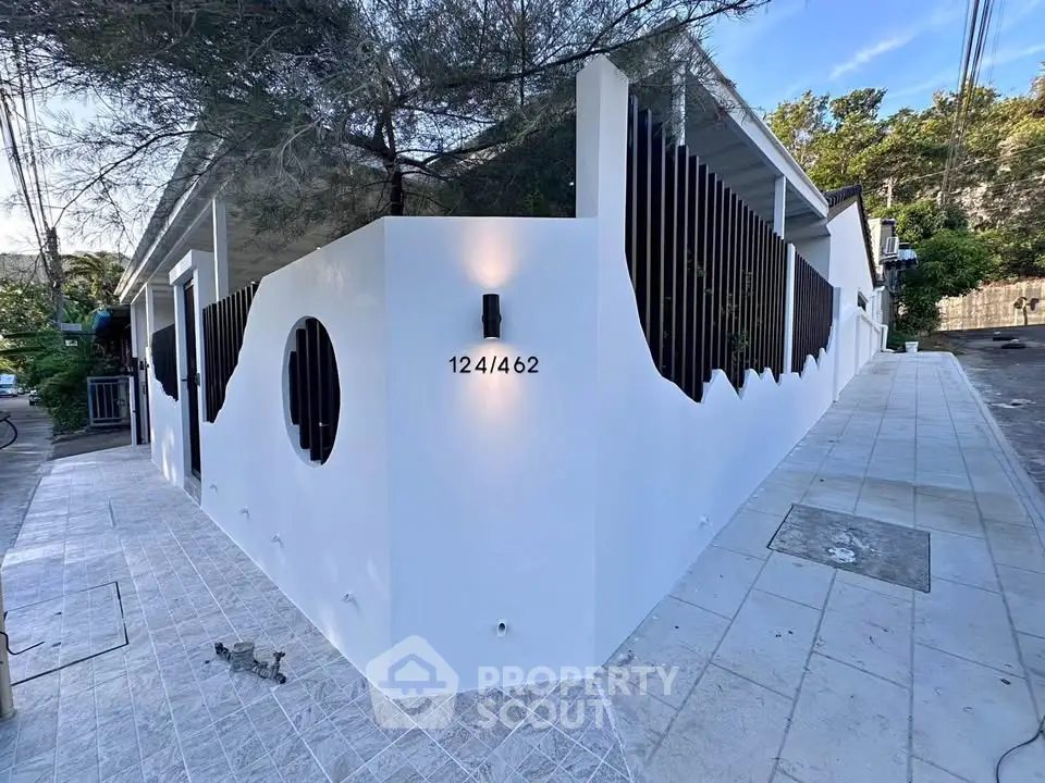 Modern white building with unique architectural design and stylish exterior lighting.