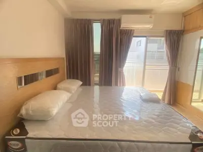 Bright bedroom with large window and balcony access, featuring a comfortable bed and modern air conditioning.