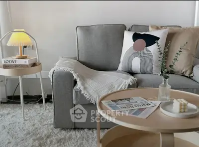 Cozy living room with modern gray sofa, stylish decor, and soft lighting.