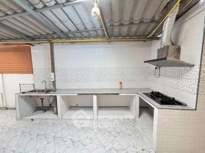 Spacious kitchen with tiled walls and gas stove, featuring open layout and modern design.