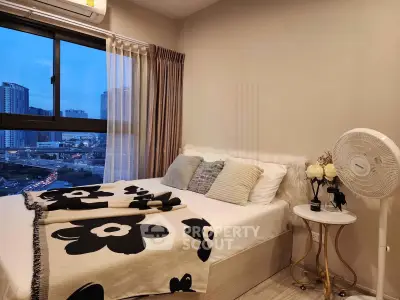 Cozy bedroom with city view, featuring stylish decor and large window for natural light.