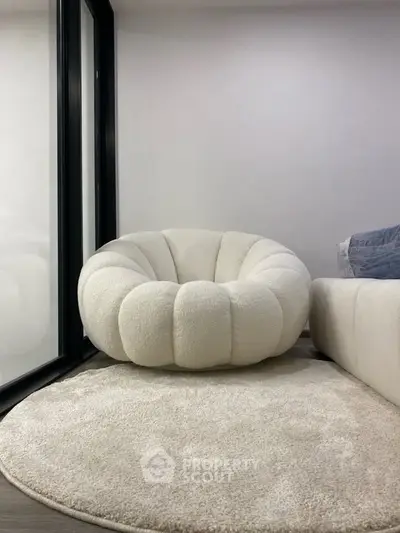 Modern living room with stylish white armchair and cozy rug, perfect for relaxation.