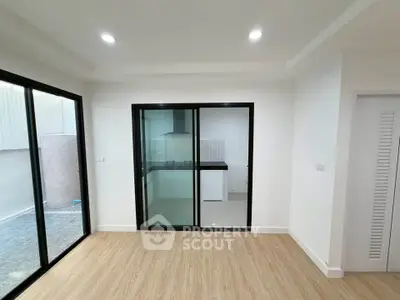 Modern living room with sliding glass doors and view into sleek kitchen