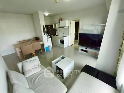 Modern living room with open kitchen, sleek furniture, and large TV, perfect for urban living.