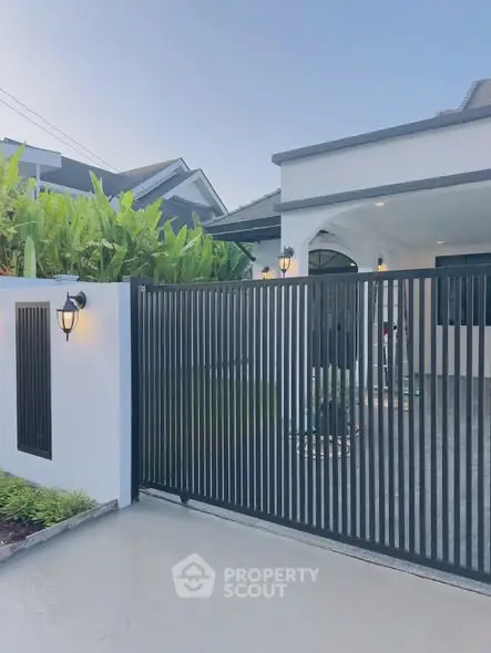 Modern house exterior with sleek gate and lush greenery