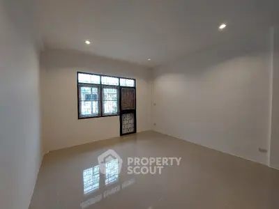 Spacious and well-lit empty room with glossy tiled flooring and multiple windows providing ample natural light, ideal for a versatile living space.