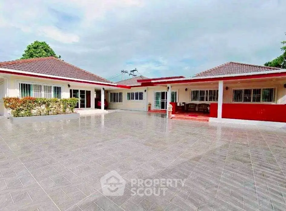 Spacious courtyard of a modern bungalow with tiled flooring and red accents.