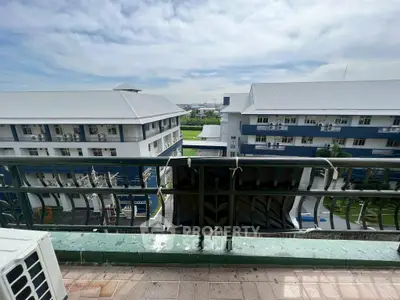 Spacious balcony with scenic view of modern buildings and lush greenery.