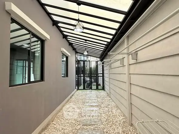 Modern covered walkway with glass roof and pebble stone path in contemporary home exterior.