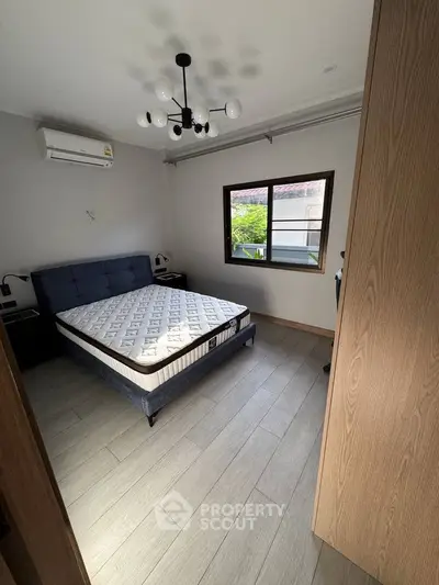 Cozy bedroom with modern lighting and air conditioning, featuring a comfortable bed and wooden flooring.