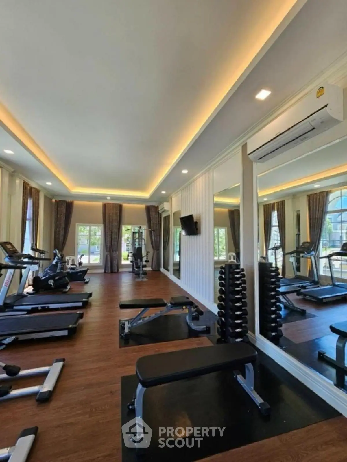 Spacious modern gym with state-of-the-art equipment and large mirrors for an enhanced workout experience.