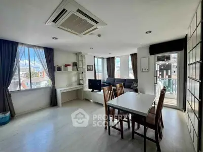 Spacious living room with dining area and large windows offering city views.