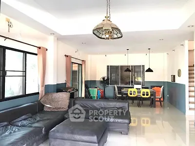 Spacious living room with modern furniture and dining area, featuring stylish lighting and large windows.
