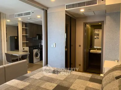 Modern studio apartment with open kitchen and washing machine, featuring stylish decor and cozy living space.