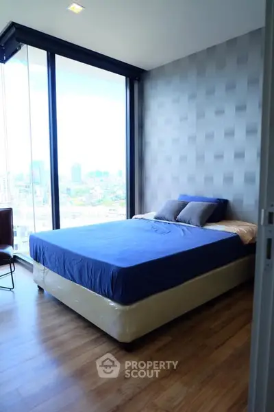 Modern bedroom with large windows offering stunning city views and stylish decor.